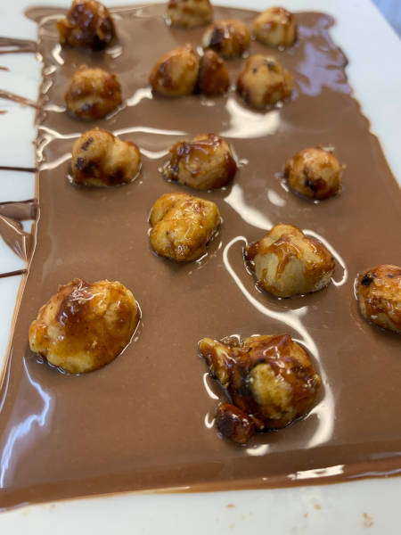 Frisch mit karamellisierten Haselnüssen bestreute Vollmilchschokolade.