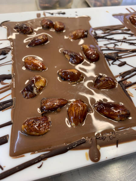 Frisch gegossene Vollmilchschokolade, von Hand mit karamellisierten Mandeln bestreut.