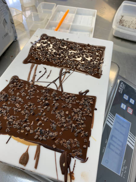 Dunkle Schokolade wird von Hand mit Kakaonibs bestreut.